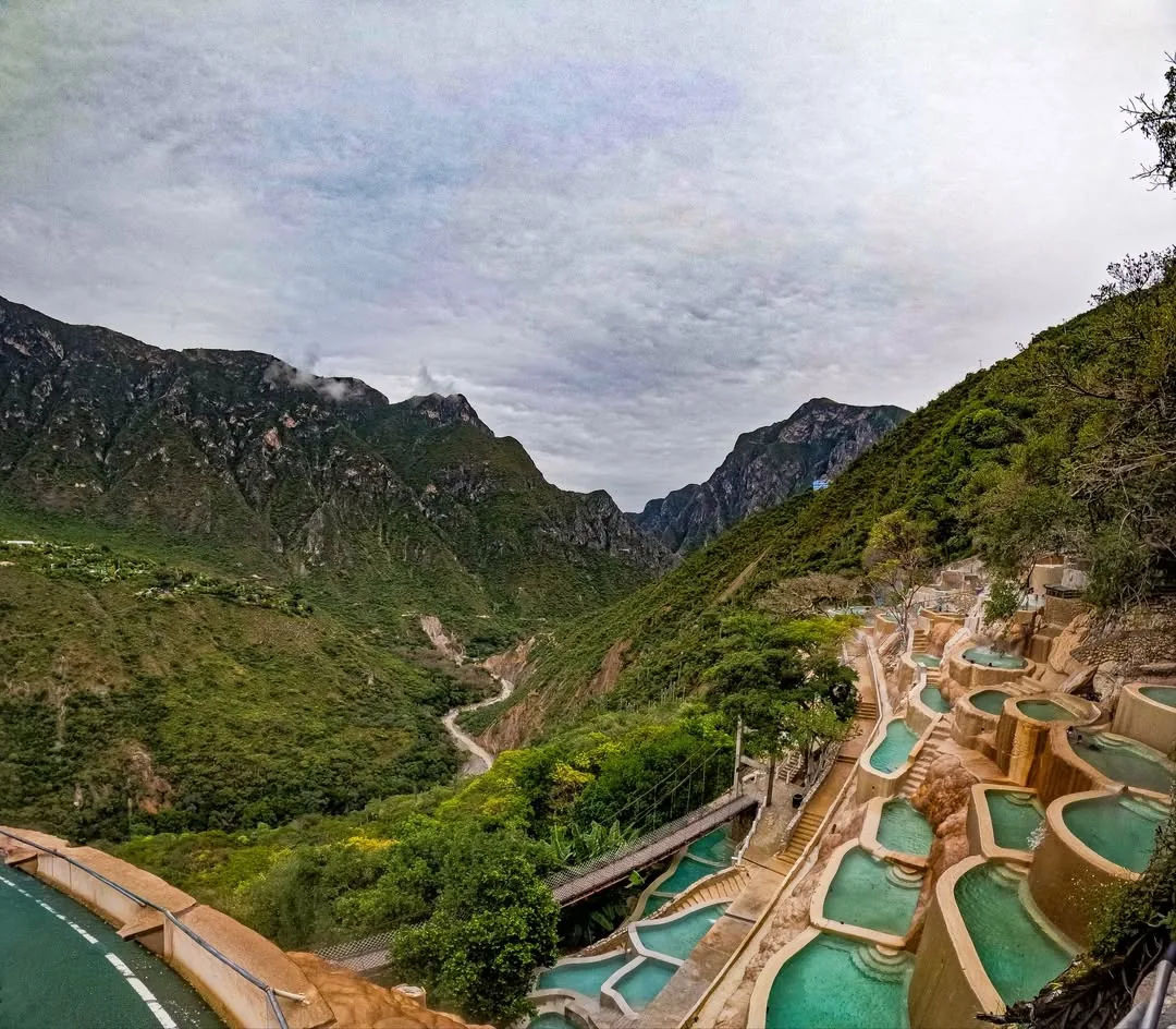 Vista panorámica del cañón con pozas termales y puente colgante