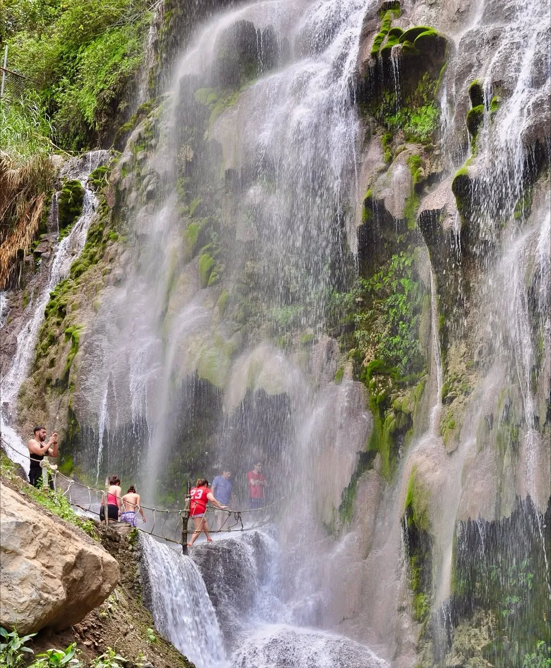 Visitantes cruzando el puente junto a la cascada de Tolantongo