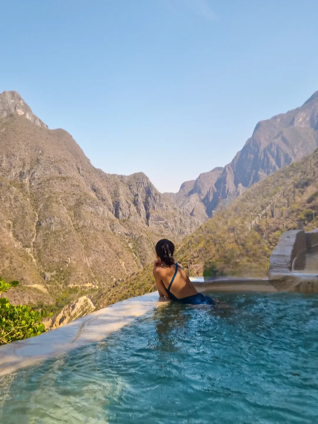 Mujer disfrutando la poza infinita con paisaje del cañón
